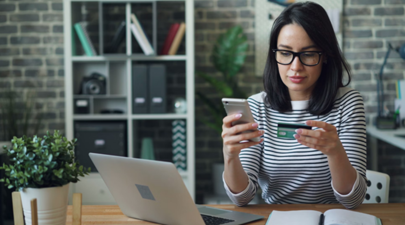 The Favor Guests Actually Keep: How to Do Custom Event Merch With Taste. (Image Credit: https://unsplash.com/photos/a-woman-sitting-at-a-table-looking-at-her-cell-phone-1JnN9QhmTGU)